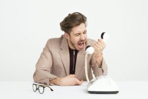 Image of a man screaming into a telephone.